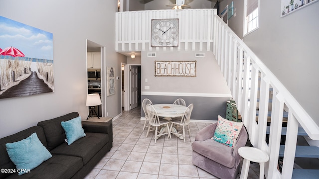 living room featuring a high ceiling, light tile patterned flooring, and ceiling fan