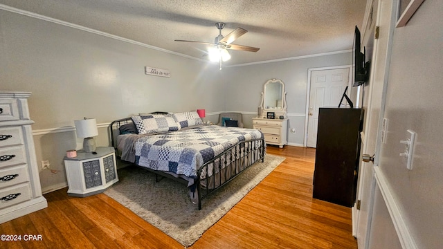 bedroom featuring a textured ceiling, crown molding, wood-type flooring, and ceiling fan