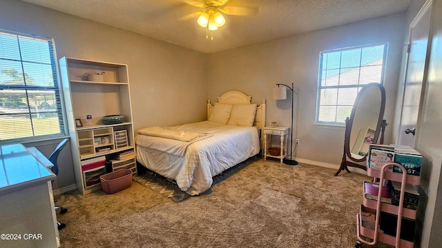 carpeted bedroom featuring ceiling fan and a textured ceiling