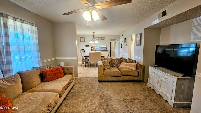 living room featuring light carpet, a textured ceiling, and ceiling fan with notable chandelier