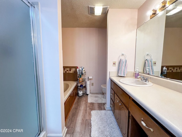 bathroom with hardwood / wood-style flooring, vanity, a tub to relax in, and a textured ceiling