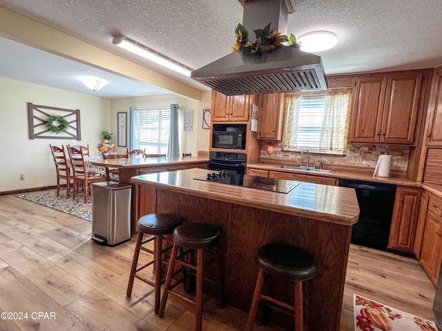 kitchen featuring sink, a center island, black appliances, and light wood-type flooring