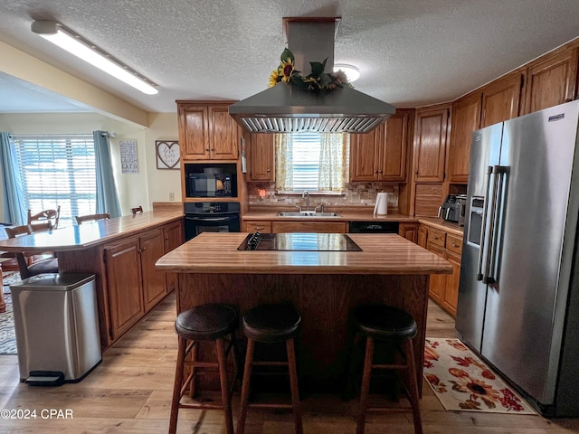 kitchen featuring kitchen peninsula, a wealth of natural light, black appliances, and light hardwood / wood-style floors