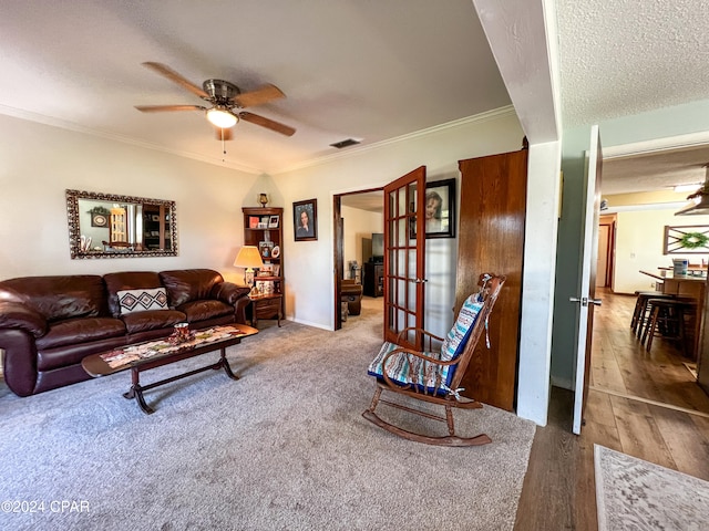 living room with ceiling fan, wood-type flooring, a textured ceiling, and ornamental molding