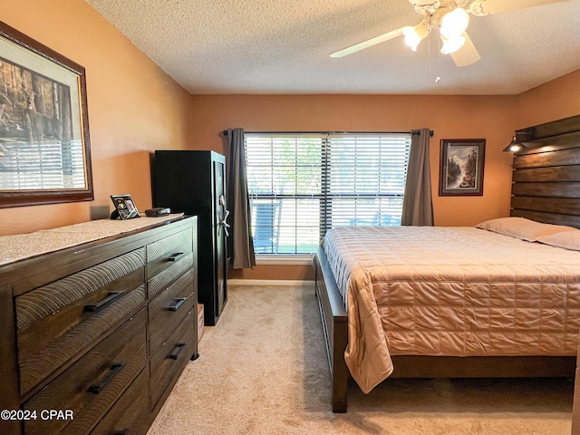 bedroom featuring light carpet, ceiling fan, and a textured ceiling