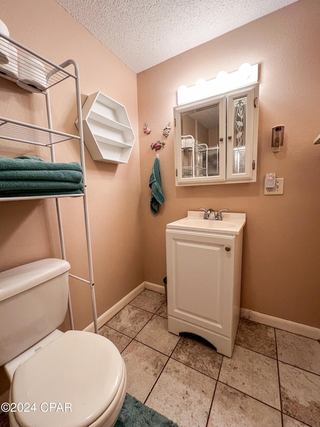 bathroom featuring tile patterned floors, vanity, toilet, and a textured ceiling