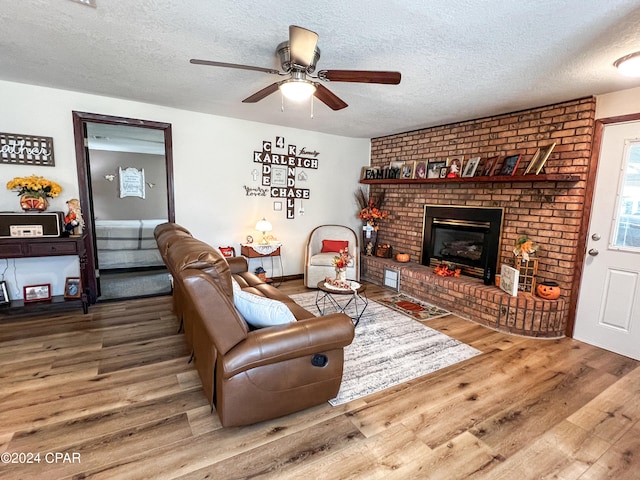 living room with hardwood / wood-style floors, a textured ceiling, and a brick fireplace