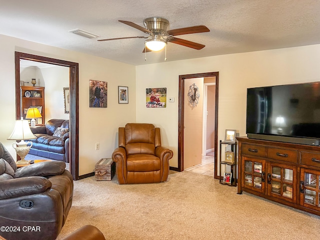 living room with a textured ceiling, ceiling fan, and light carpet