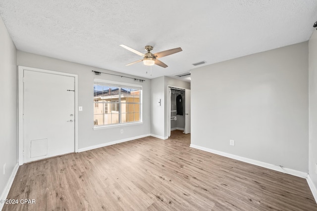 spare room with ceiling fan, light hardwood / wood-style flooring, and a textured ceiling