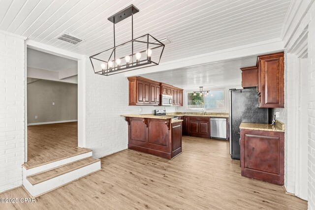 kitchen with stainless steel appliances, brick wall, a breakfast bar, and pendant lighting