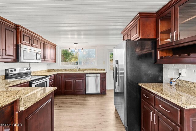 kitchen with sink, light hardwood / wood-style flooring, backsplash, stainless steel appliances, and light stone countertops