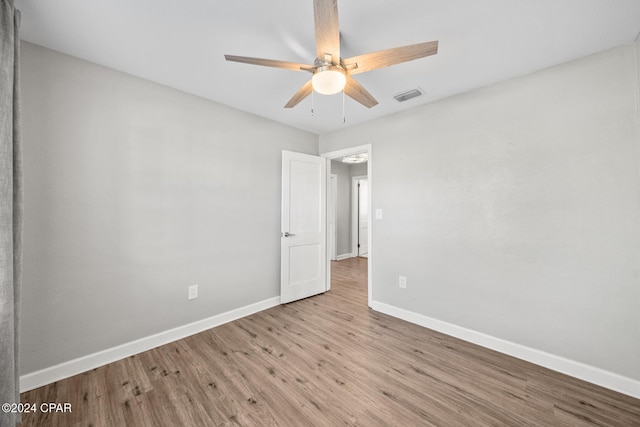 empty room with ceiling fan and light hardwood / wood-style flooring