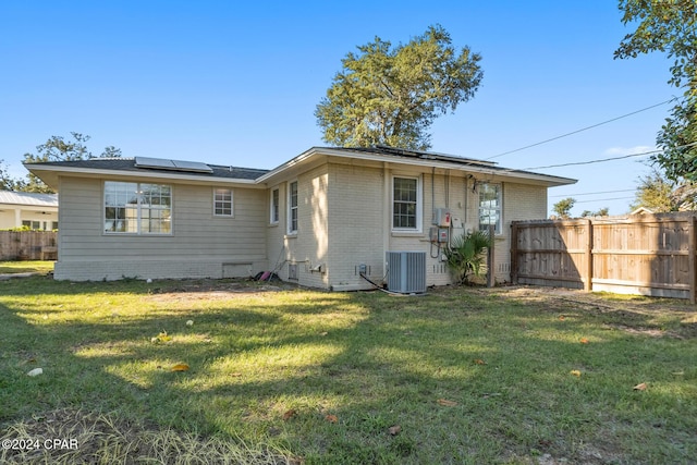 back of house with a yard, central AC, and solar panels