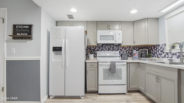 kitchen with gray cabinetry, sink, white appliances, and light hardwood / wood-style floors