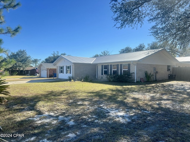 ranch-style home featuring brick siding, metal roof, a front lawn, and fence