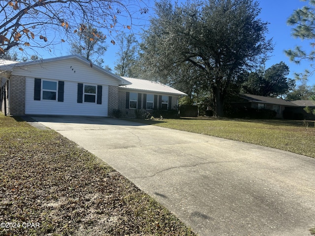 ranch-style house featuring driveway, brick siding, and a front lawn