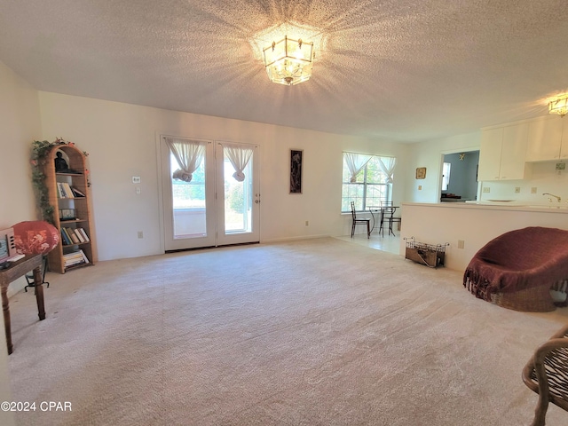 17680 Margaret St, Blountstown, FL 32424 - living room with a notable chandelier, french doors, light colored carpet, and a textured ceiling