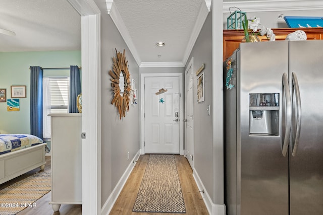 doorway featuring crown molding, a textured ceiling, and light wood-type flooring