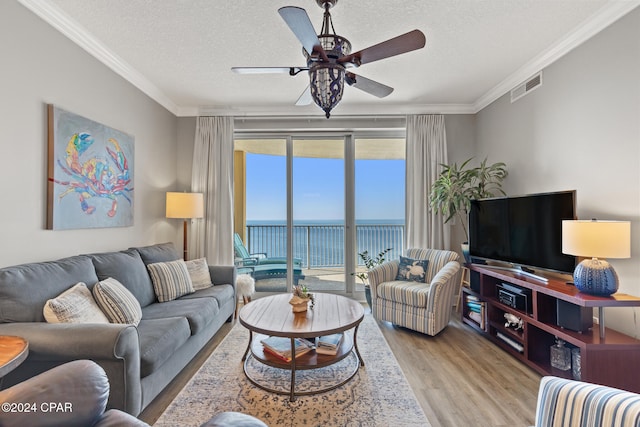 living room with crown molding, a textured ceiling, light wood-type flooring, and ceiling fan