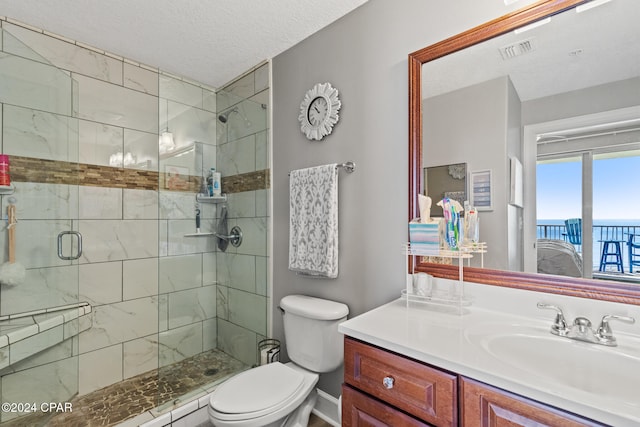 bathroom featuring toilet, a textured ceiling, a shower with shower door, and vanity