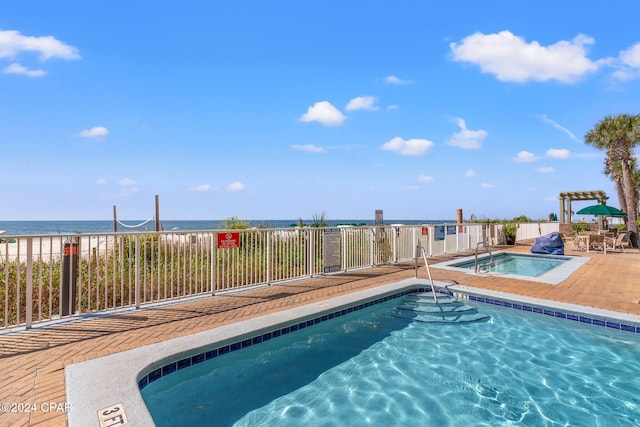 view of pool with a hot tub and a water view