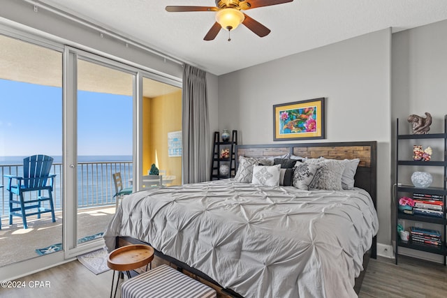 bedroom featuring a water view, ceiling fan, access to outside, and hardwood / wood-style floors