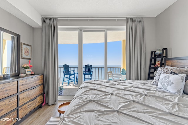 bedroom with light wood-type flooring, multiple windows, and access to outside