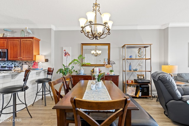 dining area featuring light hardwood / wood-style floors, crown molding, and an inviting chandelier