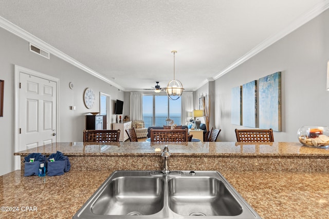 kitchen featuring hanging light fixtures, ceiling fan, a textured ceiling, ornamental molding, and sink