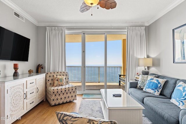 living room with a water view, crown molding, light hardwood / wood-style flooring, and plenty of natural light