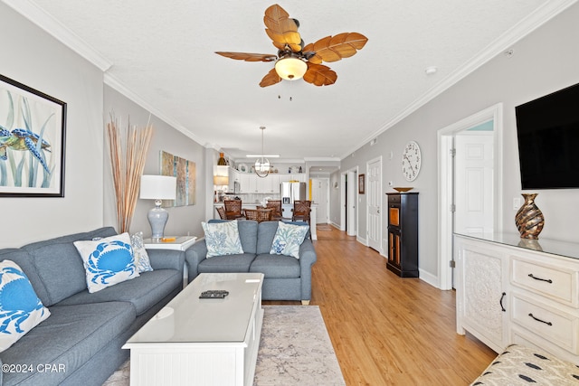 living room featuring crown molding, light hardwood / wood-style flooring, and ceiling fan with notable chandelier