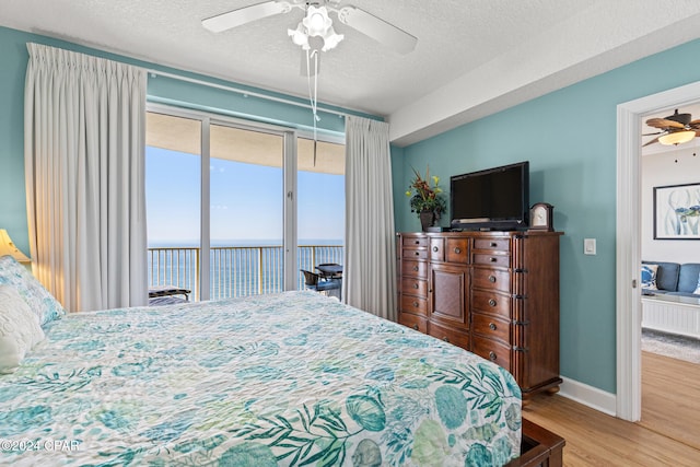 bedroom featuring light hardwood / wood-style floors, access to outside, a textured ceiling, and ceiling fan