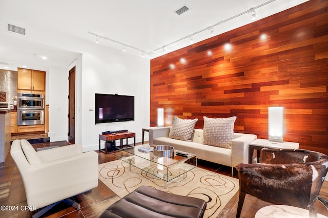 living room with wooden walls, track lighting, and hardwood / wood-style flooring