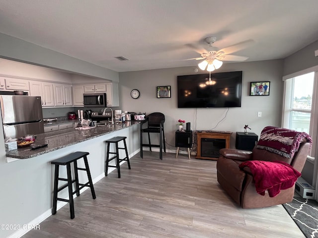 living room featuring light hardwood / wood-style flooring, sink, and ceiling fan