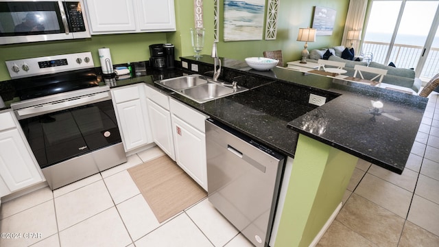 kitchen with kitchen peninsula, appliances with stainless steel finishes, light tile patterned floors, and white cabinets