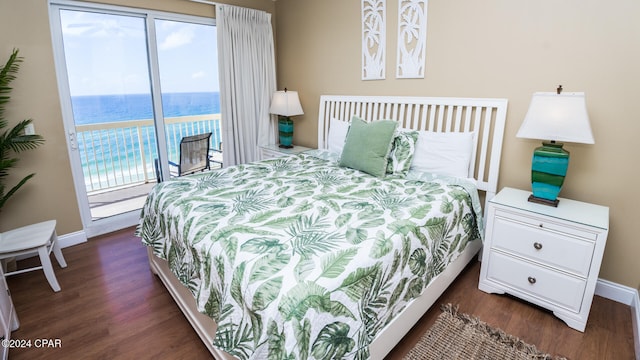 bedroom featuring dark wood-type flooring, access to outside, and a water view