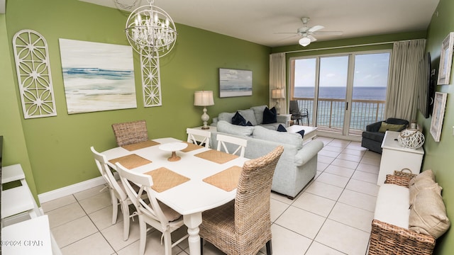 dining area featuring ceiling fan with notable chandelier, light tile patterned floors, and a water view