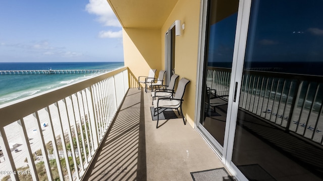 balcony with a water view and a view of the beach