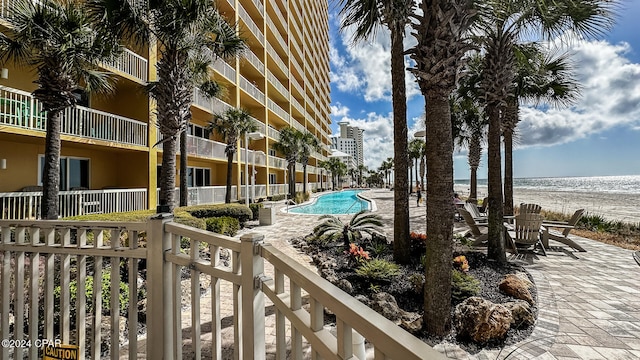 view of pool featuring a view of the beach, a water view, and a patio area