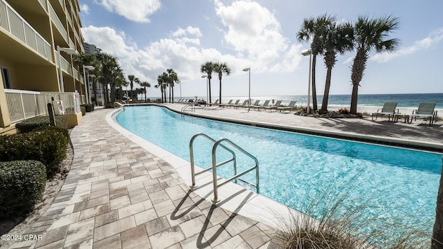 view of pool featuring a water view and a patio