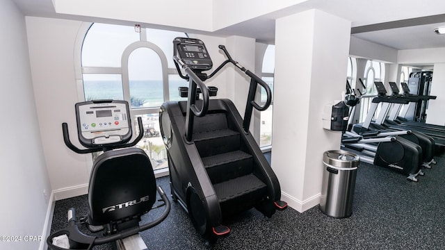 exercise room featuring a water view