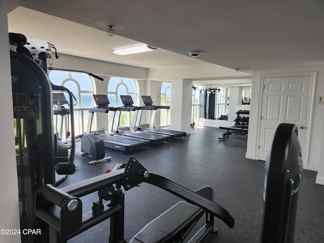 exercise room with a water view and a textured ceiling