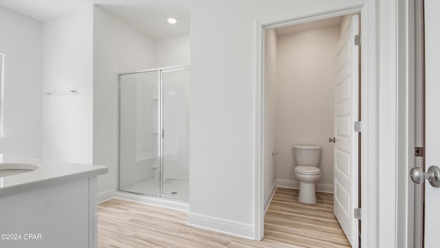 bathroom with vanity, toilet, a shower with shower door, and hardwood / wood-style floors