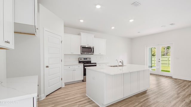 kitchen with sink, appliances with stainless steel finishes, white cabinetry, and light wood-type flooring