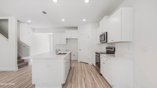 kitchen featuring a kitchen island with sink, sink, white cabinetry, appliances with stainless steel finishes, and light hardwood / wood-style floors