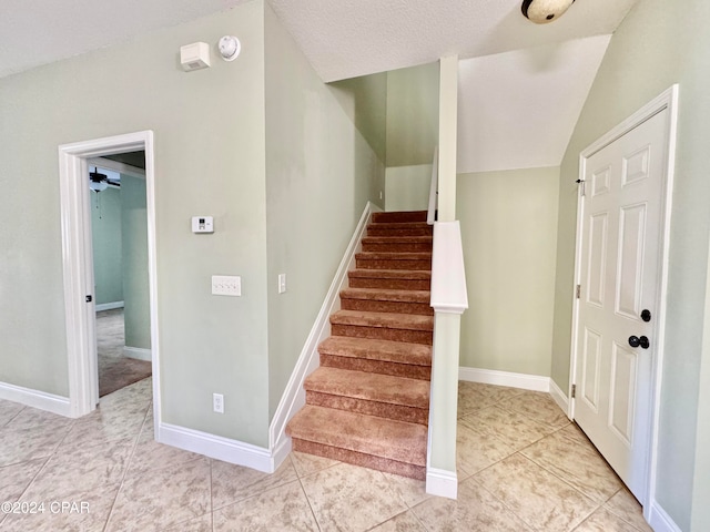 stairs featuring tile patterned floors, a textured ceiling, vaulted ceiling, and ceiling fan