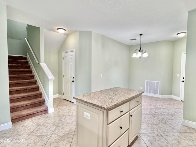 kitchen with a center island, light tile patterned floors, pendant lighting, and an inviting chandelier