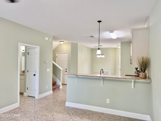 kitchen featuring kitchen peninsula, decorative light fixtures, and a breakfast bar area