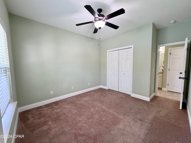 unfurnished bedroom featuring dark colored carpet, ceiling fan, and multiple windows