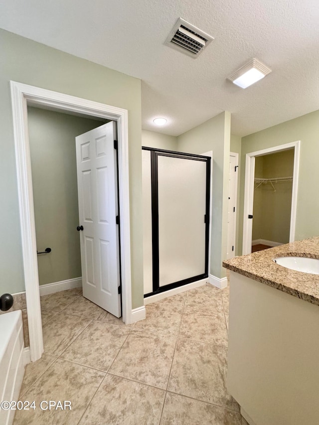 bathroom featuring tile patterned floors, vanity, separate shower and tub, and a textured ceiling